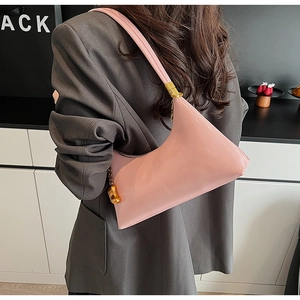 Detail der rosa Lackleder-Hobo-Tasche mit goldenem Elefantenanhänger an der Schulter