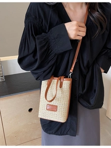 Vertical woven straw crossbody phone bag with brown leather handles and adjustable strap