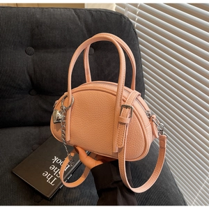 Détail d'un sac à main rose clair à texture litchi avec fermeture éclair et breloque
