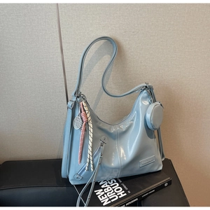 Detail of light blue glossy tote bag with decorative zipper and tennis racket charm