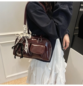 Dettaglio della borsa Boston in vernice bordeaux con fiocco in pizzo e ciondolo a perla