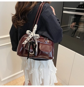 Detalle del bolso de hombro en charol rojo oscuro con lazo de lunares y colgantes metálicos