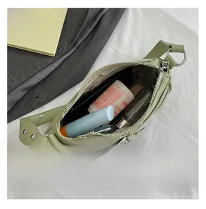 Spacious interior of a light green crossbody bag showing daily essentials and zip pocket