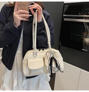 Detalle de bolso de hombro crema con lazo decorativo y colgante de cuentas