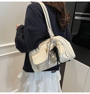 Detalle de bolso crema con lazo de encaje y cinta de adorno llevado por una modelo