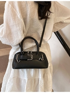 Minimalist black shell handbag for women with silver hardware on a white pleated dress