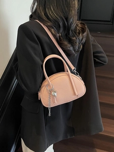 Sac Boston en cuir grainé rose avec pendentif coeur sur des marches en bois