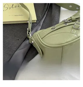 Detail of light green faux leather shoulder bag with silver eyelets and buckle accents