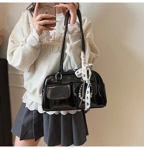 Detalle de bolso de hombro en charol negro con lazos de encaje y cadena de cuentas plata