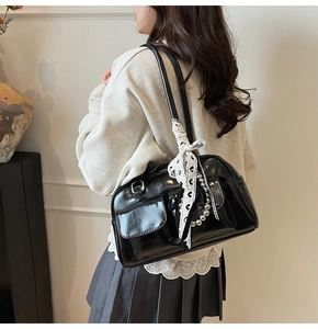 Detalle de bolso de hombro en cuero negro brillante con lazos de encaje y perlas