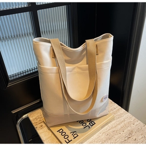 Detail of canvas tote bag with good luck patch and reinforced khaki webbing handles