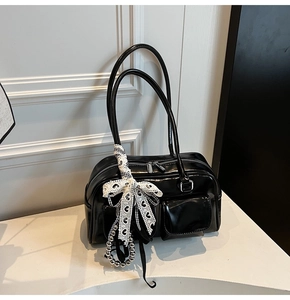Detalle de bolso de hombro en charol negro brillante con lazo de encaje y cadena de metal