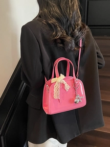 Glossy pink Boston handbag with lace bow and silver dog charm shown from a back view
