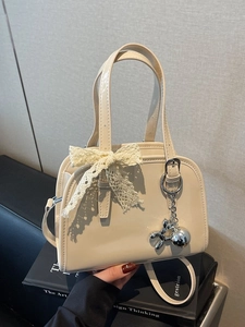 Cream patent leather Boston bag with lace bow and silver dog charm in life scene