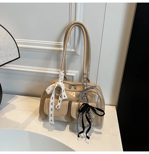 Detalle de bolso de hombro en charol beige con lazos decorativos y cintas elegantes