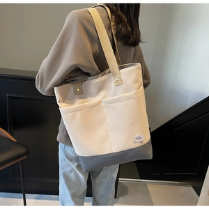 Detail view of canvas tote bag with contrast grey bottom and dual front utility pockets