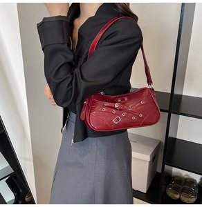 Detail of red patent leather shoulder bag with buckles and silver eyelets in moto style
