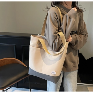 Detail of canvas tote bag with contrast stitching and side pocket on a female shoulder