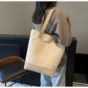 Detail of canvas tote bag with contrast outer pockets and 'good luck' circular label