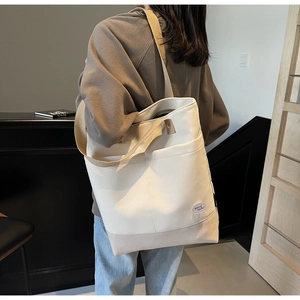 Close-up of beige canvas tote bag featuring khaki trim and good luck embroidery patch