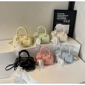 Six colorful mini Boston bags with pearl bow charms displayed on minimalist pedestals