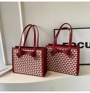 Detailed view of red heart pattern woven fabric tote with leather bow and handles