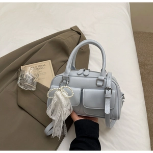 Close-up of light blue bowling bag with front pockets and pearl lace bow charm