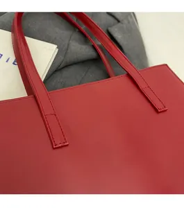 Close-up of precise stitching on red leather tote bag with elegant handle detail
