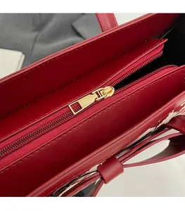 Close-up of the smooth gold-toned metal zipper on a premium red leather tote bag