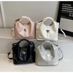 Detail shot showing minimalist leather handbags with iconic metal triangle logos and straps