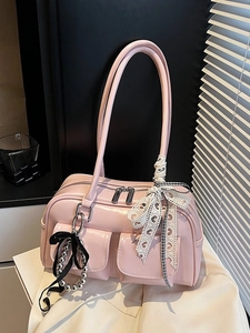 Bolso Boston rosa con cinta de encaje de corazón y colgantes metálicos en mesa blanca
