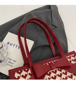 Detail of red heart-patterned tote bag with a large leather bow on a lifestyle background