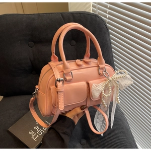 Détail du sac Boston en similicuir rose avec nœud en dentelle et perles élégantes