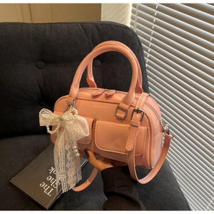 Sac bowling rose brillant avec breloque en dentelle sur un canapé noir