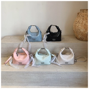 Detail view of colorful mini dumpling bags in blue, pink, black and green with pearl chains