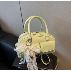 Detail of light green patent leather Boston bag with lace bow and pearl charm