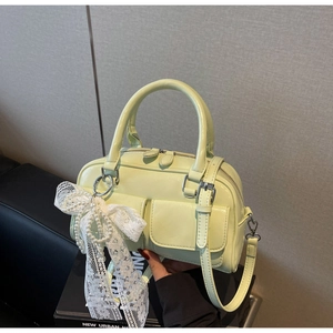 Détail du sac Boston vert clair avec finition brillante, nœuds dentelle et perles