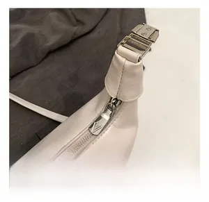 Close-up of premium silver metal zipper and smooth cream leather texture on crossbody bag