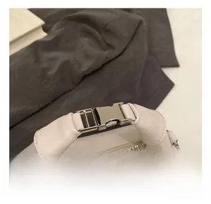 Detail shot of the cream crossbody bag showing leather handle and silver metal buckle