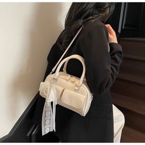 Sac Boston crème avec nœuds en dentelle et breloques en perles dans un décor élégant