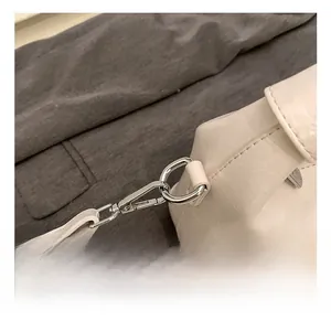 Detail shot of silver metal hook and stitching on white leather crossbody bag