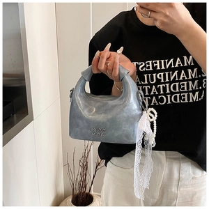 Detail of metallic blue crossbody bag with lace pearl charm and metal logo lettering
