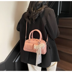 Vue détaillée du sac bowling rose brillant avec nœud en perles et bandoulière réglable