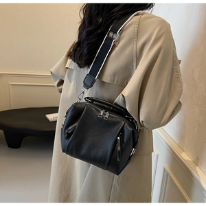 Close-up of black lychee grain leather Boston bag with trendy striped wide strap