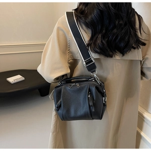 Detail of black pebbled leather crossbody bag with contrasting wide shoulder strap