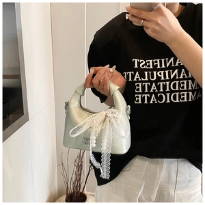 Mirror selfie showing mint green crossbody bag with lace bow and pearl pendant detail