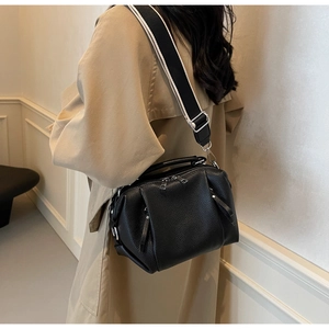 Close-up of black litchi pattern leather bag with striped wide fabric shoulder strap