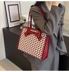 Close-up of houndstooth tote bag with red bow detail worn by model in studio