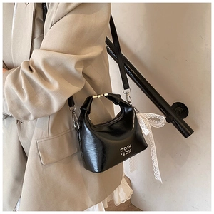 Close-up of black leather dumpling bag with silver hardware and white lace ribbon detail
