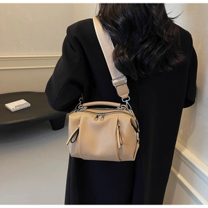 Detailed view of camel Boston bag with lychee texture and wide fabric shoulder strap